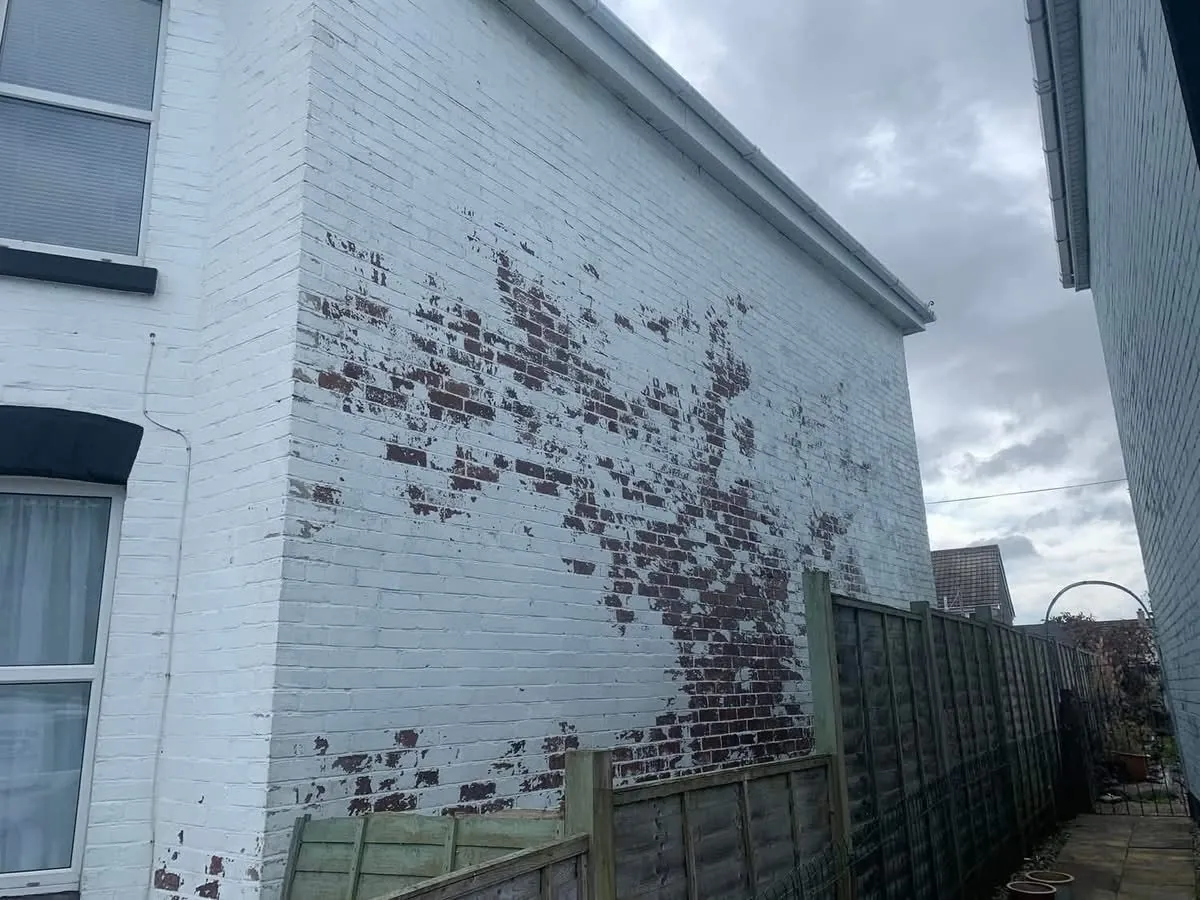 Peeling paint on a brick wall before redecoration in Cullompton